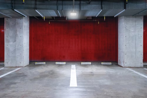 Underground parking garage illuminated by a ceiling-mounted canopy light, providing bright, even lighting across the parking spaces.